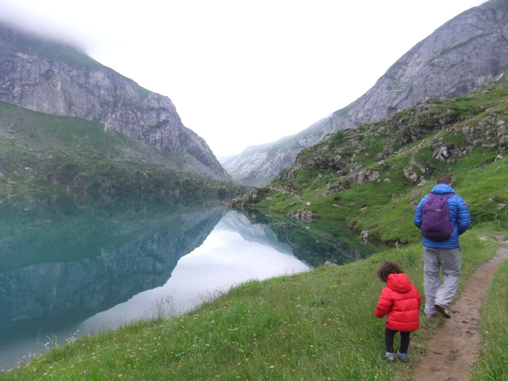 padre e hijo caminando junto a un lago turquesa en los hautes pyrenees