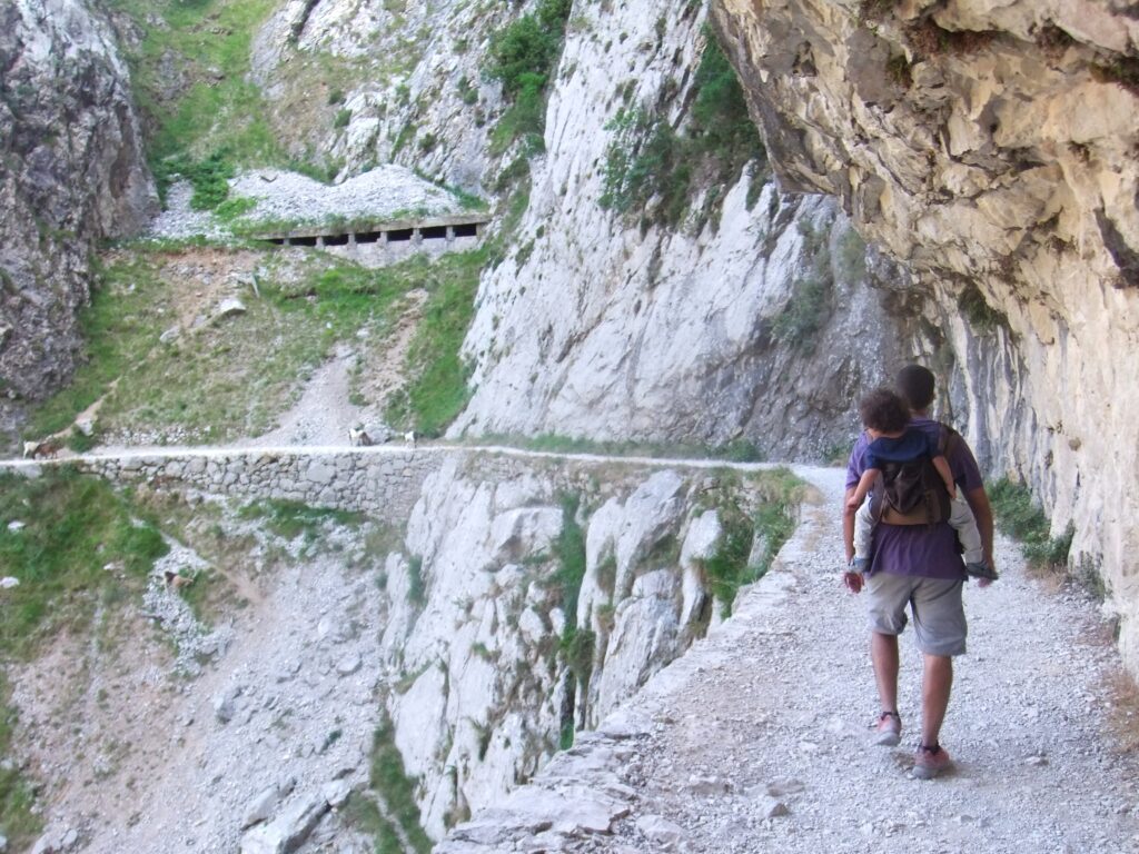 padre porteando a su hijo en la mochila de porteo en la ruta del cares