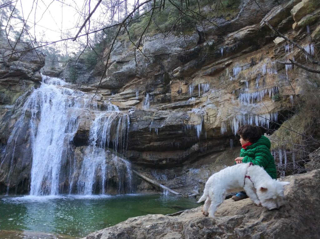 niño frente a la cascada congelada dels gorgs de la cabana en campdevanol