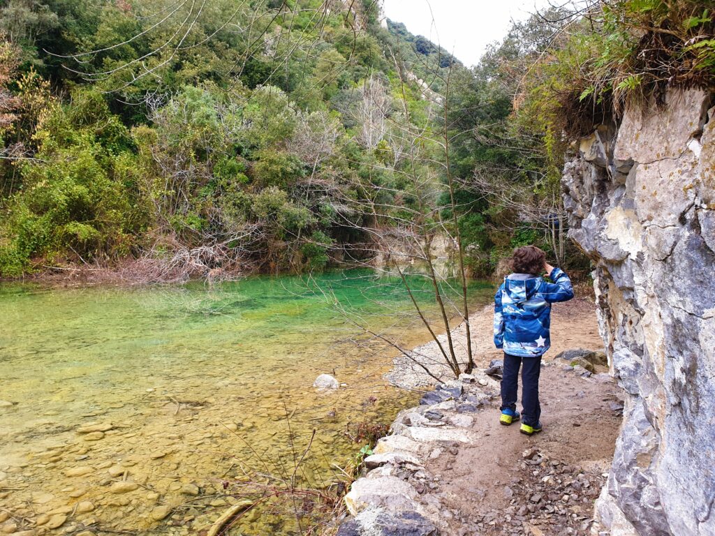 Niño haciendo senderismo por al lado de un río turquesa en La Garrotxa