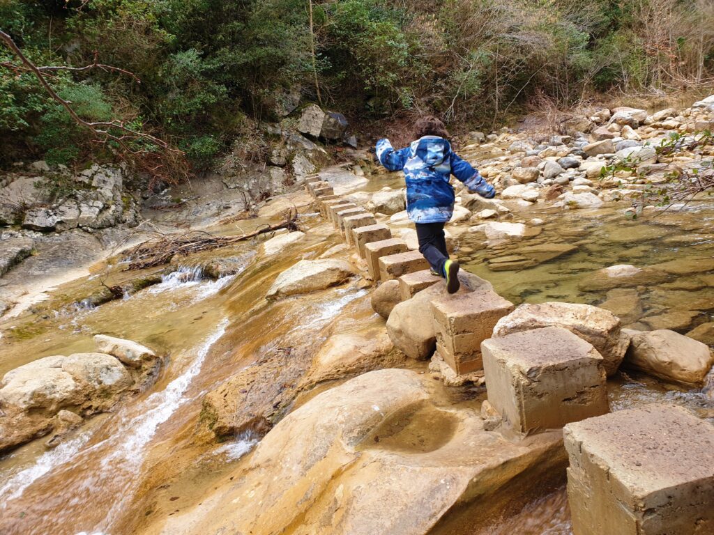 Niño cruzando un río en la ruta al Salt del Brull en la garrotxa