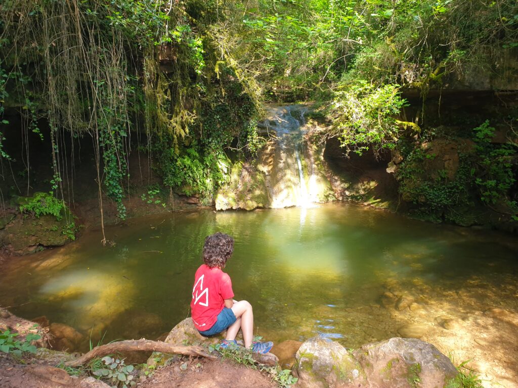 Niño sentado delante de la cascada de figaró