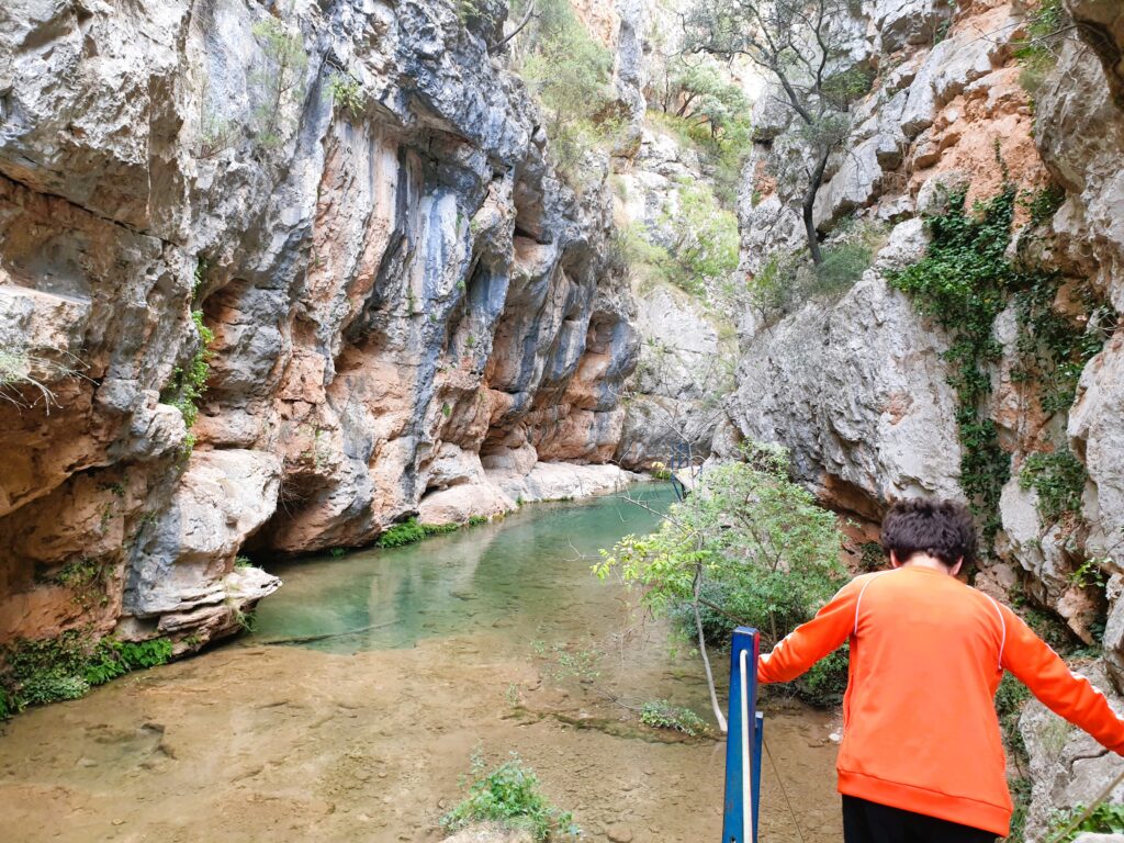 Niño bajando por la pasarela de los Estrechos del Ebron con agua turquesa, Teruel