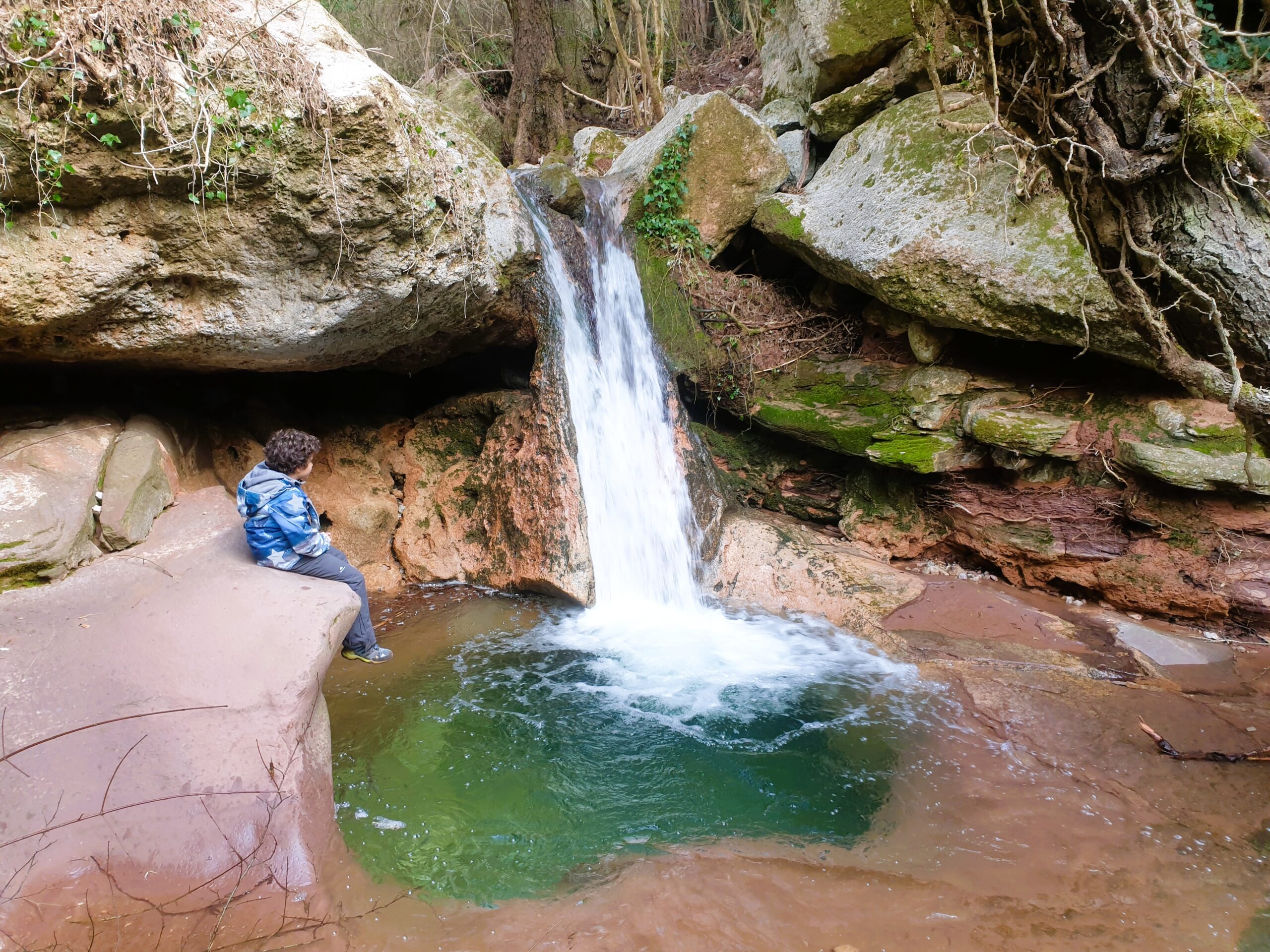 Niño junto a cascada en la ruta del Gorg de la Sort, Aiguafreda, Montseny