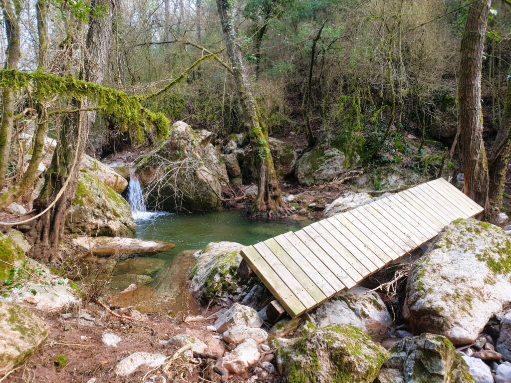 Puente de madera en la ruta del Gorg de la Sort con cascada al fondo, Aiguafreda