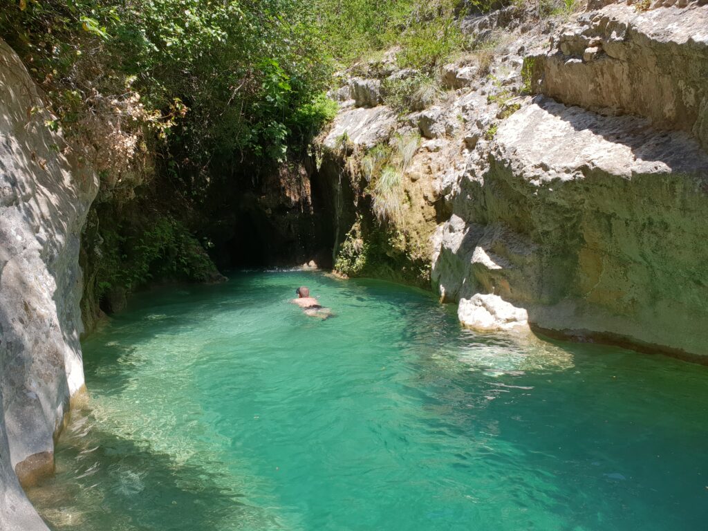 Persona nadando por el estrecho de agua turquesa del Forat de Bulí hacia el túnel