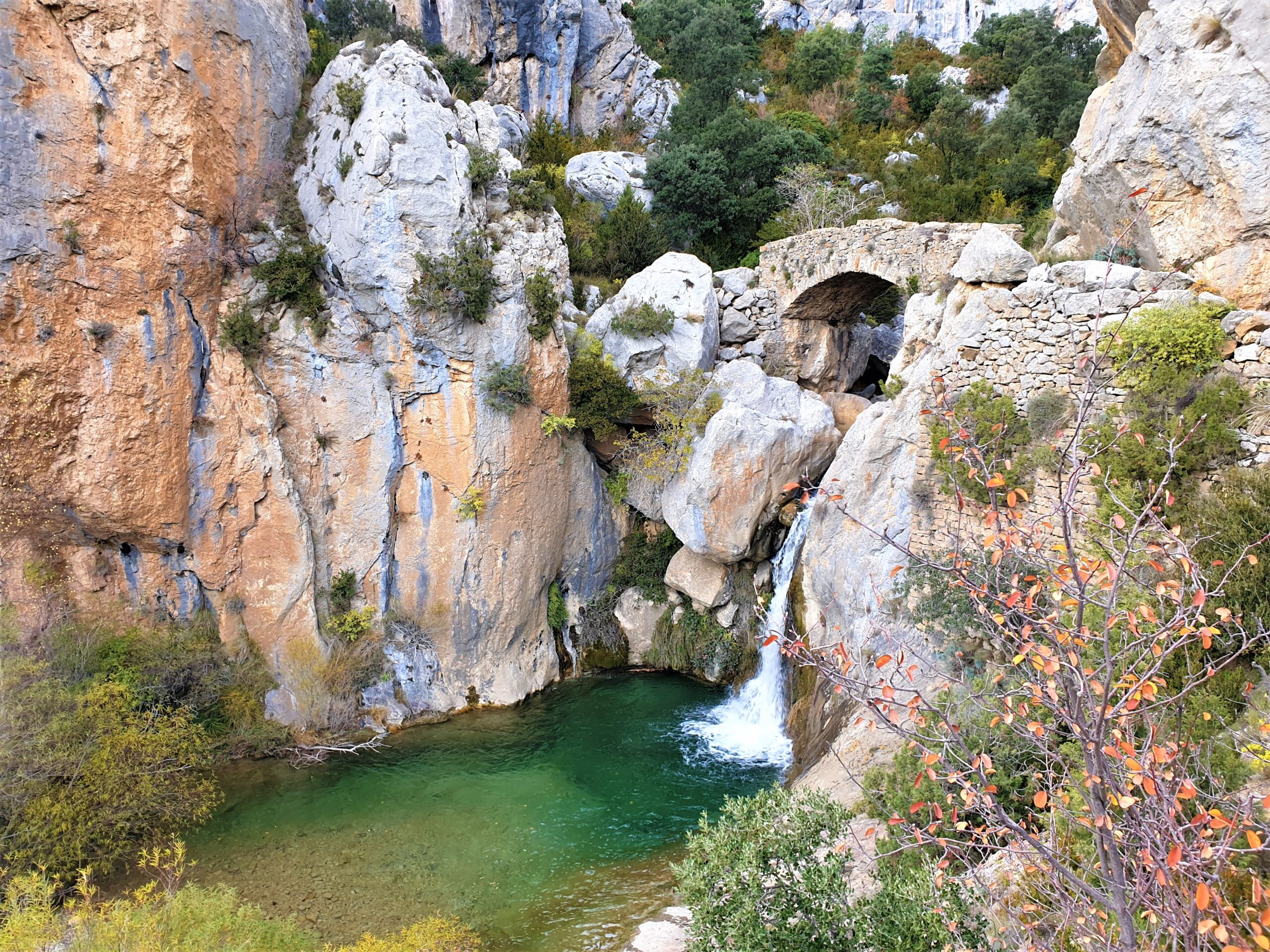 Cascada de Bóixols con poza verde y puente medieval en otoño, Pallars Jussà